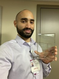 Darnell smiles, holding his award.