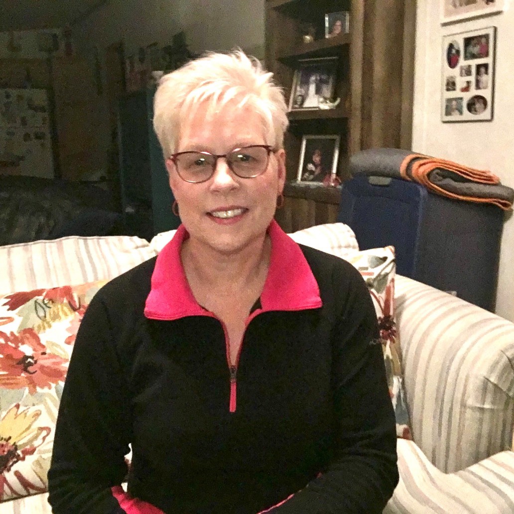 Woman sitting in her home, smiling.