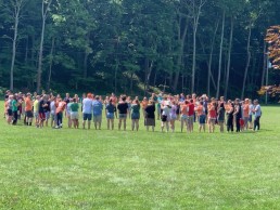 Group of teens in grass at camp.